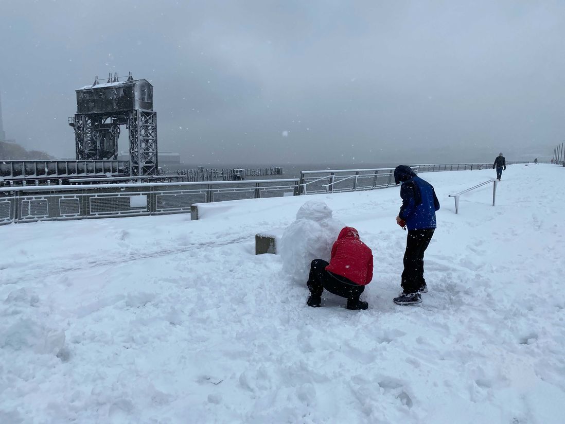 A mother and son make a snow penguin in Riverside Park.